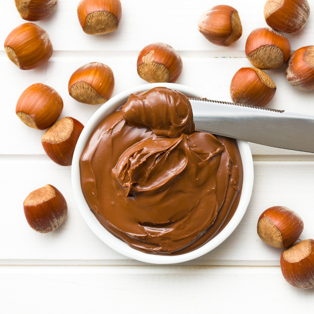Hazelnut spread on a wooden table with a knife. Perfect combo of chocolate and hazelnuts!