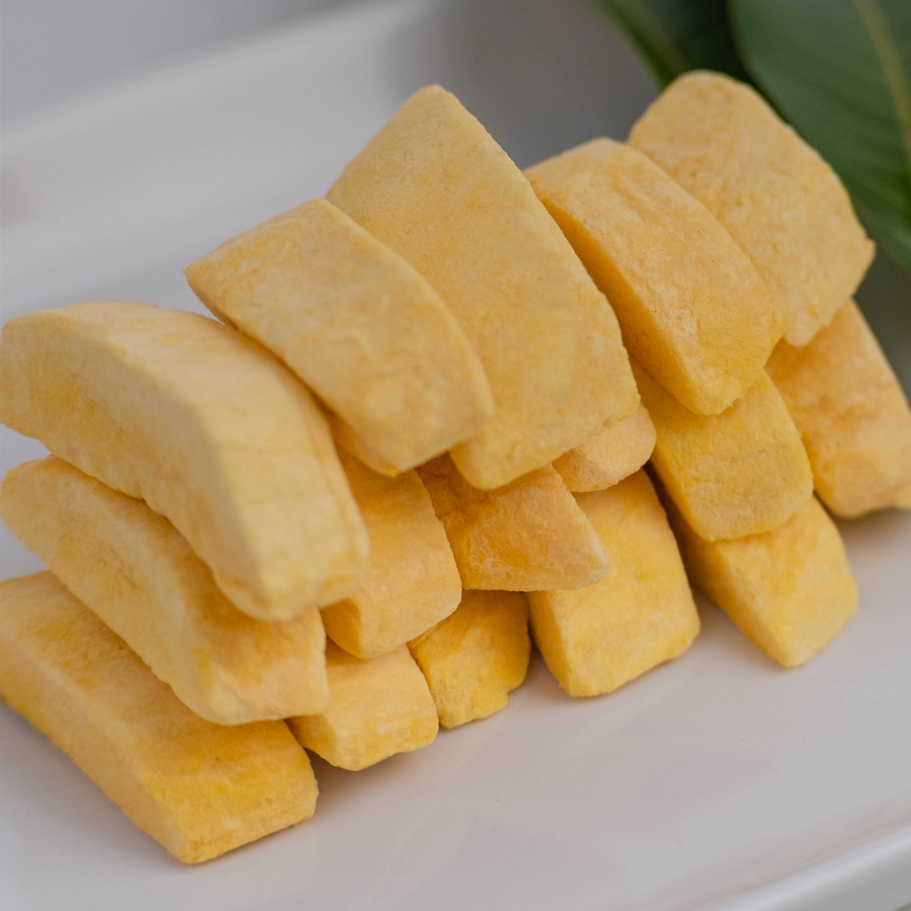 Stack of thick, freeze-dried mango slices on a white surface.