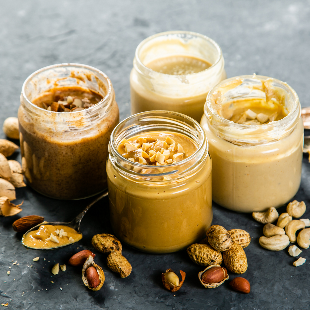 A variety of nut butters including peanut, almond, and cashew butter, displayed in a jar.