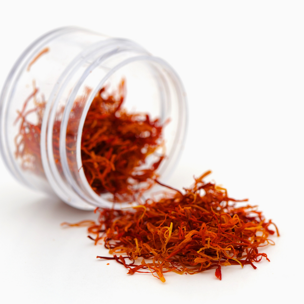 A jar of dried saffron on a white surface, adding vibrant color and flavor to culinary creations.
