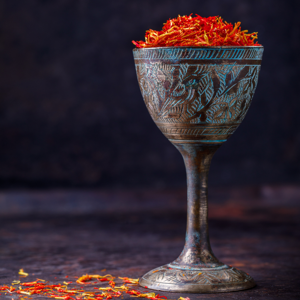 A glass cup filled with dried saffron, a vibrant spice known for its fascinating origins, distinct flavor and golden color.