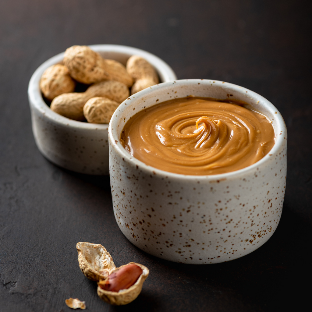 Peanut butter and peanuts in separate bowls, a healthy option for a nutritious snack.