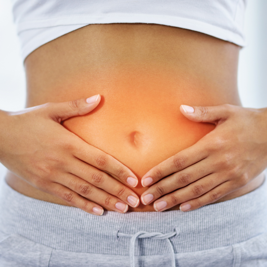 Close-up of a person holding their stomach with an orange glow, symbolizing gut health and digestion.